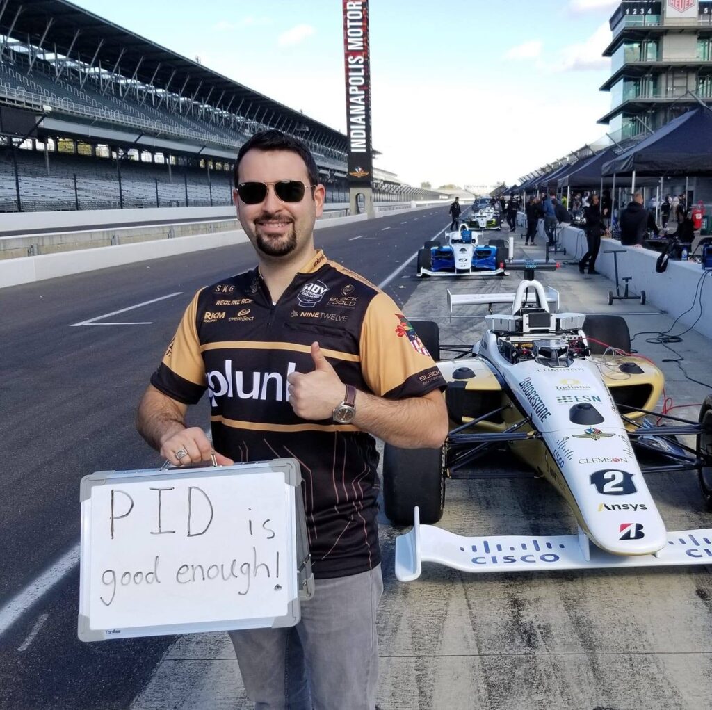 Daniel at Indianapolis Motor Speedway holding a sign that says PID is good enough